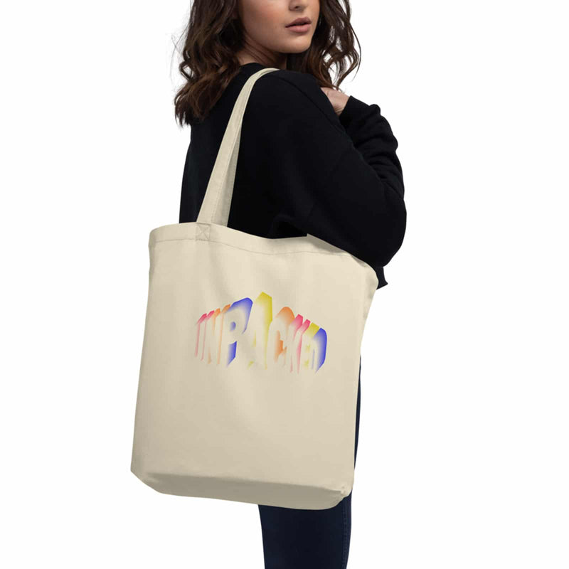 model holding cream colored tote bag with the Unpacked brand logo imprinted on it