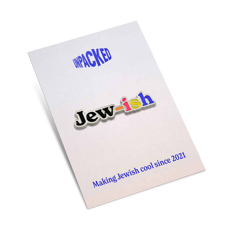 multicolored silver enamel pin that reads "jew-ish" on a backing card that has the Unpacked brand logo, and a tagline that reads "Making Jewish cool since 2021"